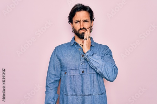 Young handsome hispanic bohemian man wearing hippie style over pink background touching mouth with hand with painful expression because of toothache or dental illness on teeth. Dentist