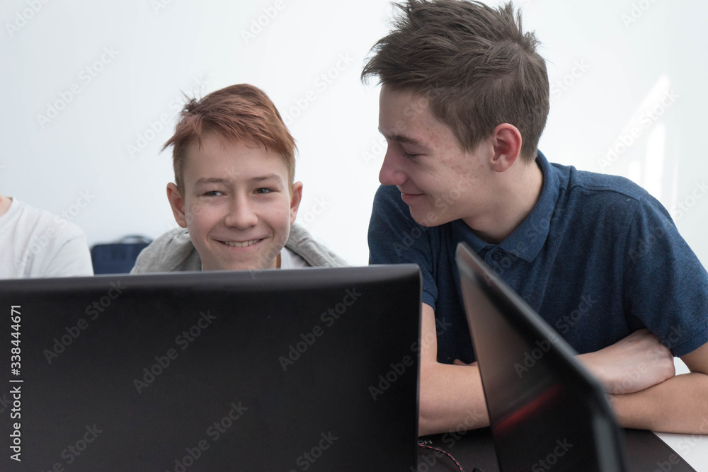 the boys are working with a laptop. students study in the classroom. Teenagers work on their laptop. Design lesson at school. the boys are working with a laptop. students study in the classroom. Teenagers work on their laptop. Design lesson at school.