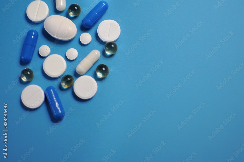 Scattered deifferent pills on blue table. Medicine against COVID-19 and diseases