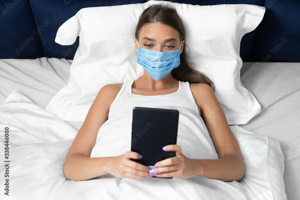 Woman In Medical Mask Using Tablet Watching Movie At Home Woman In Medical Mask Using Tablet Watching Movie At Home