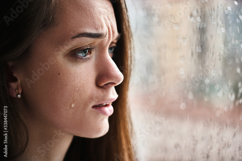Canvas Print Upset crying woman with tears eyes suffering from emotional shock, loss, grief, life problems and break up relationship near window with raindrops