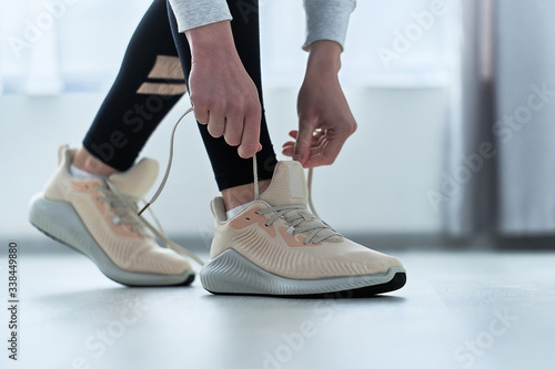 Fitness woman ties shoelaces on beige sneakers and get ready for running and workout. Do sport and be fit. Sports people with healthy sporty lifestyle