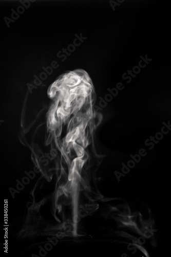 Abstract figures of white flowing steam from a diffuser on a black background. photo