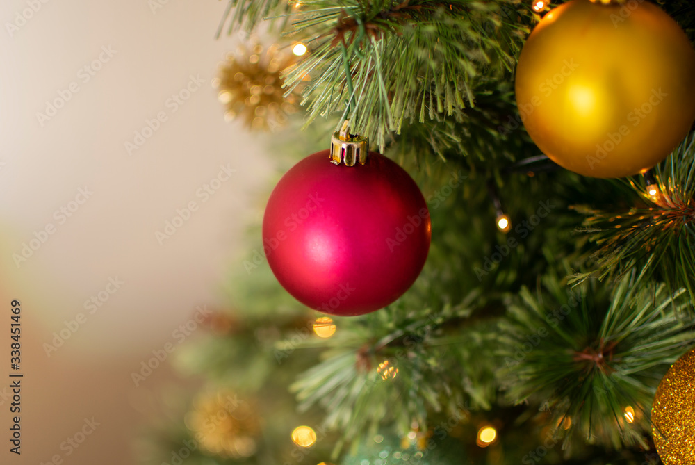 Red and yellow Christmas balls hanging from the green tree, close up view Red and yellow Christmas balls hanging from the green tree, close up view