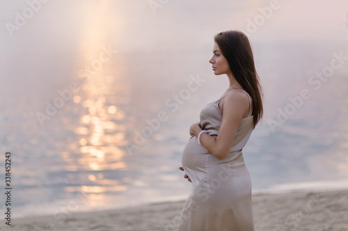 Konstfotografi Beautiful pregnant woman on the coast sunset