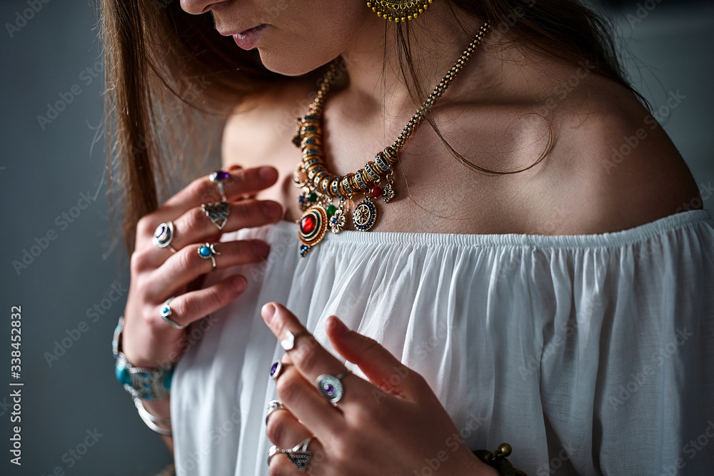Stylish boho chic woman wearing white blouse with golden necklace and silver rings. Fashionable indian hippie gypsy bohemian outfit with imitation jewelry details accessories