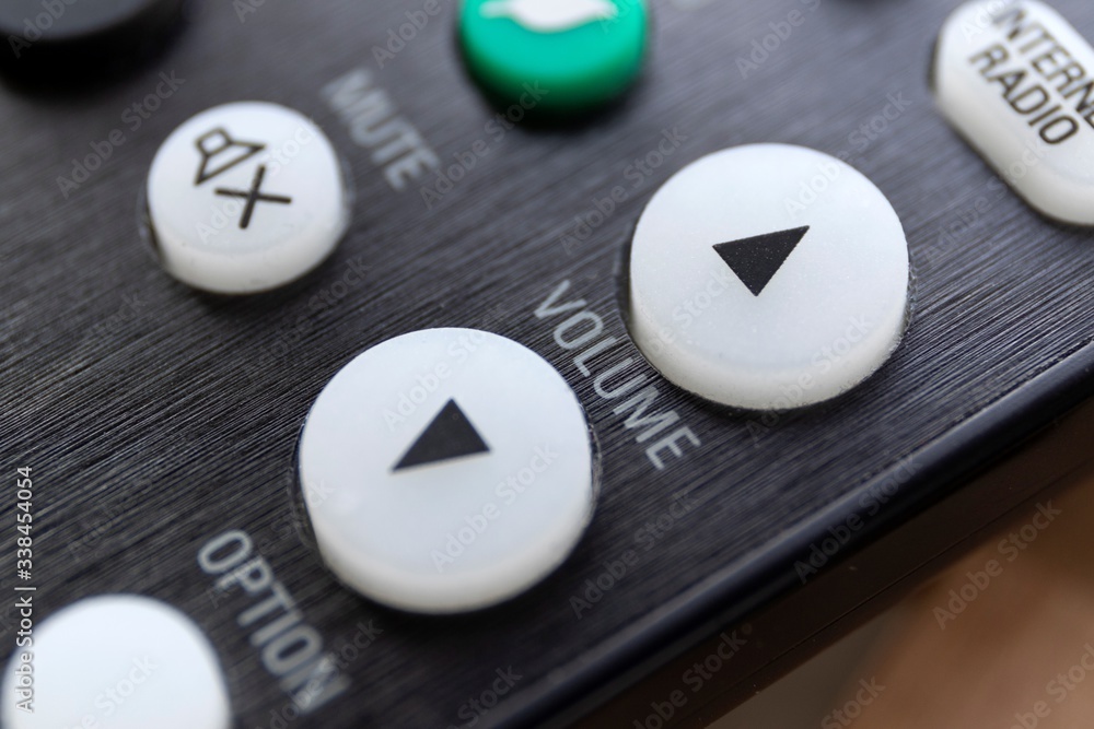 A close up portrait of the volume up and down buttons on a radio, television or surround sound system, used to alter the sound level. In the background the mute button is visible but blurred. A close up portrait of the volume up and down buttons on a radio, television or surround sound system, used to alter the sound level. In the background the mute button is visible but blurred.