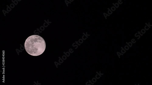 Full moon moving alone in the dark sky without stars in the spring night