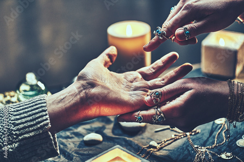 Wallpaper Mural Fortune teller woman wearing silver rings with turquoise stone and bracelets reads palm lines during fortune telling around candles and other magic accessories