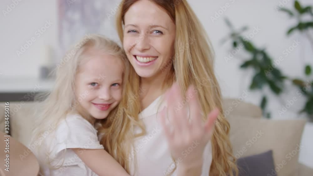 Slowmo of happy young woman and adorable little girl with blond hair laughing and hugging while beckoning someone off camera Slowmo of happy young woman and adorable little girl with blond hair laughing and hugging while beckoning someone off camera