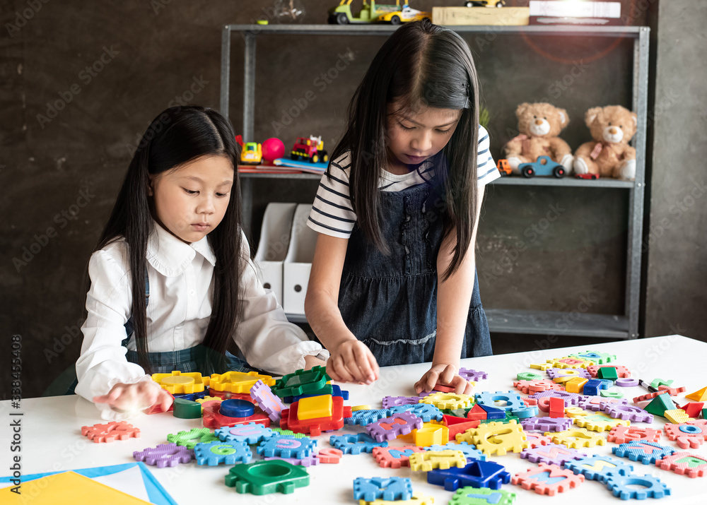 Fototapeta premium Two little girl are playing plasticine together,with interested feeling,at home studio,Lens flare effect,blurry light around