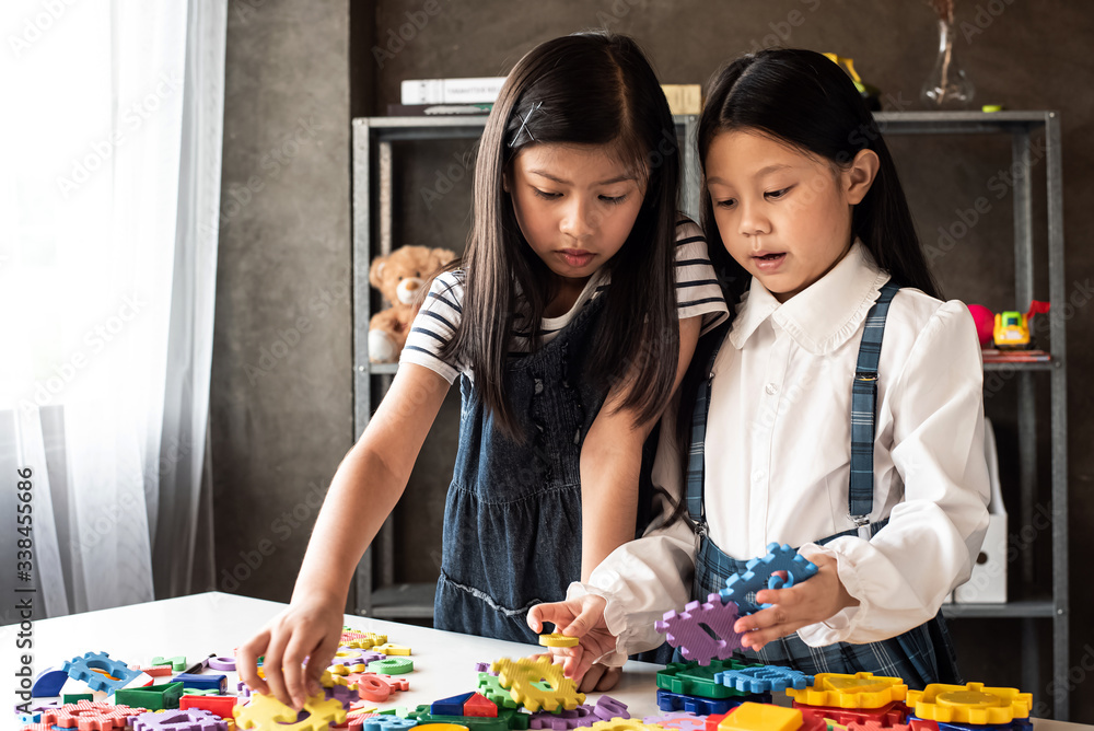 Fototapeta premium Two little girls are playing plasticine together,with interested feeling,at home studio,Lens flare effect,blurry light around