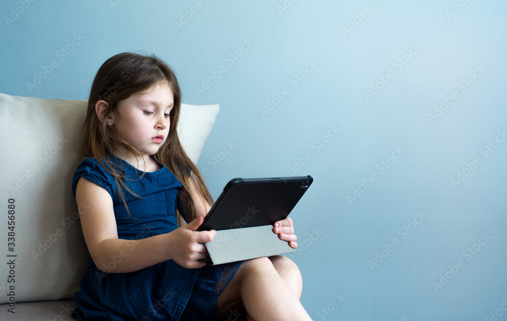 The child uses the tablet for self-education during quarantine. The girl is studying online. A child is looking for information on the Internet. The child uses the tablet for self-education during quarantine. The girl is studying online. A child is looking for information on the Internet.