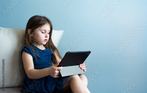 The child uses the tablet for self-education during quarantine. The girl is studying online. A child is looking for information on the Internet.
