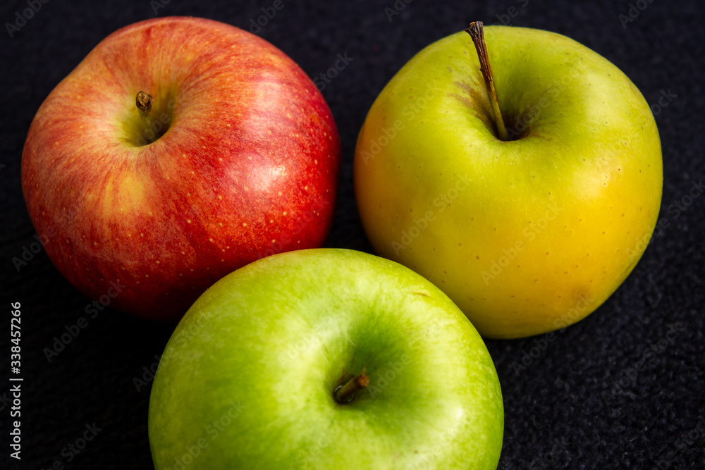 Three apples, one green and two red and yellow on a dark background Three apples, one green and two red and yellow on a dark background