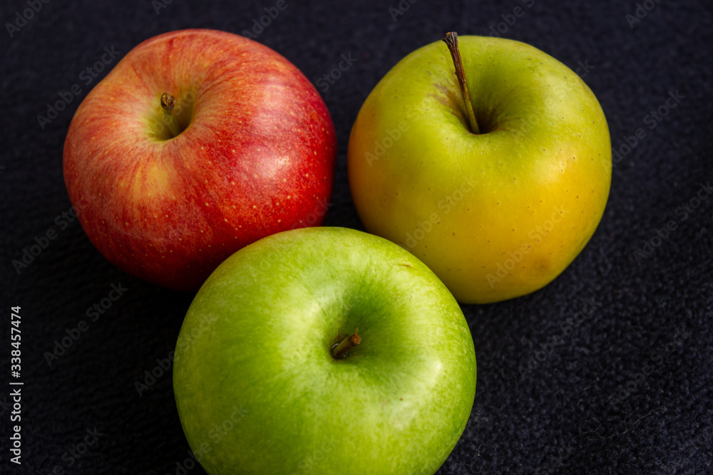 Three apples, one green and two red and yellow on a dark background Three apples, one green and two red and yellow on a dark background