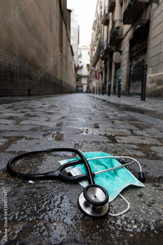 empty street due to the confinement of the coronavirus. there is a stethoscope and a mask as conceptp of the doctors killed due to the pandemic photo