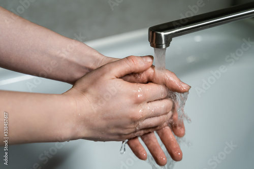 Good hygiene during the coronavirus pandemic. Woman washes hands in hot running water with soap