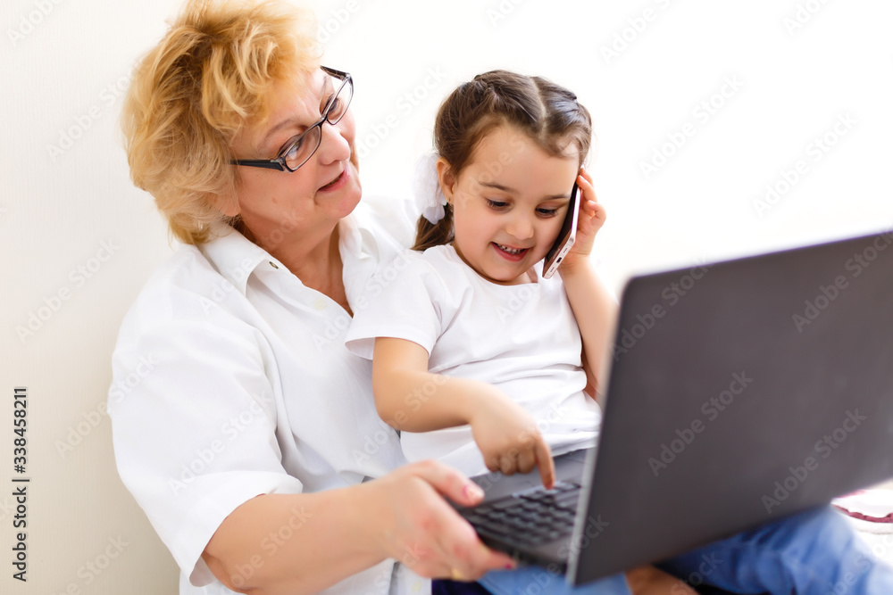 Smart little girl grandchild sit on couch shopping online with excited senior grandmother, teen granddaughter and smiling granny buy on internet browsing laptop relaxing at home together Smart little girl grandchild sit on couch shopping online with excited senior grandmother, teen granddaughter and smiling granny buy on internet browsing laptop relaxing at home together