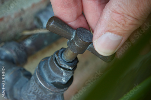Mans hand turning garden tap/faucet