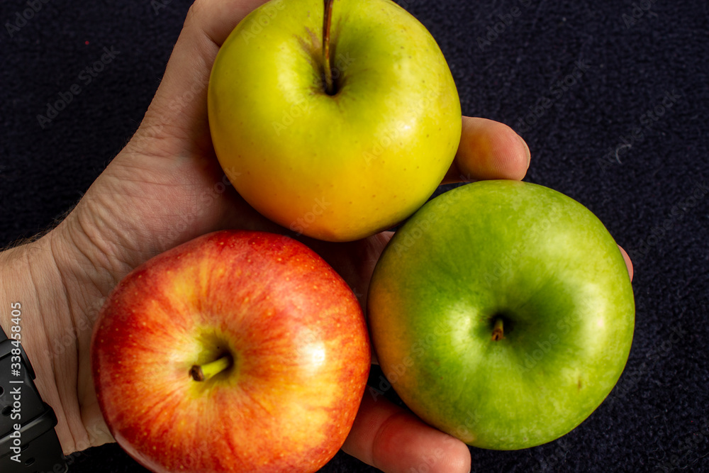 Three apples, one green and two red and yellow in the hand. Three apples, one green and two red and yellow in the hand.