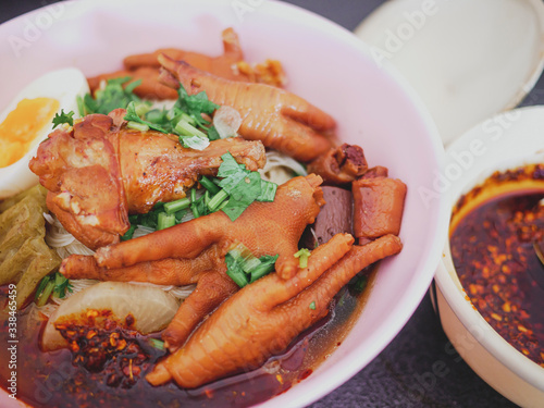 Food of Thailand. Braised Chicken Noodle Consisting of blood and chicken feet Yellow egg noodles, steamed bitter gourd, bean sprouts ,sliced spring onions and braised pepper in cup.