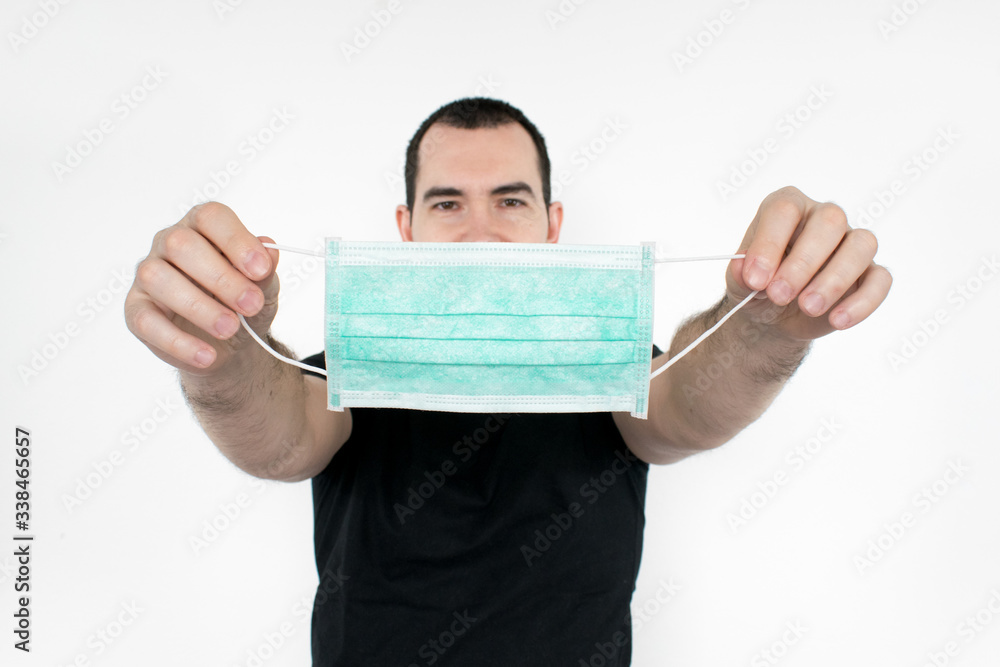caucasian  male man young. stand at white background,  hold mask gesture in two hands. coronavirus symbol, protect yourself save lifes and put on.  Coronavirus.