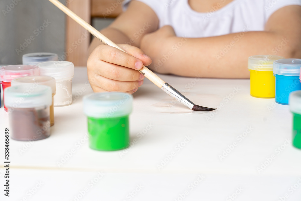 the girl leads with a brush on a white sheet of paper, will paint, stay at home the girl leads with a brush on a white sheet of paper, will paint, stay at home