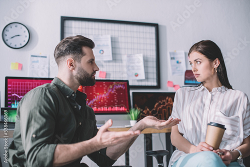 Data analyst planning work with colleague holding paper cup in office
