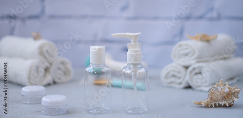 Plastic containers. Spa composition, recreation and hospitality. Beauty and skin care concept. Plastic bottles, lens containers and white towels on a light background