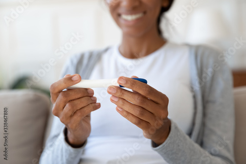 Close up of happy black girl smiling and hold pregnancy or ovulation test in hands. Desired, planned and successful pregnancy, rejoice and celebrate positive result, concept of health and motherhood photo