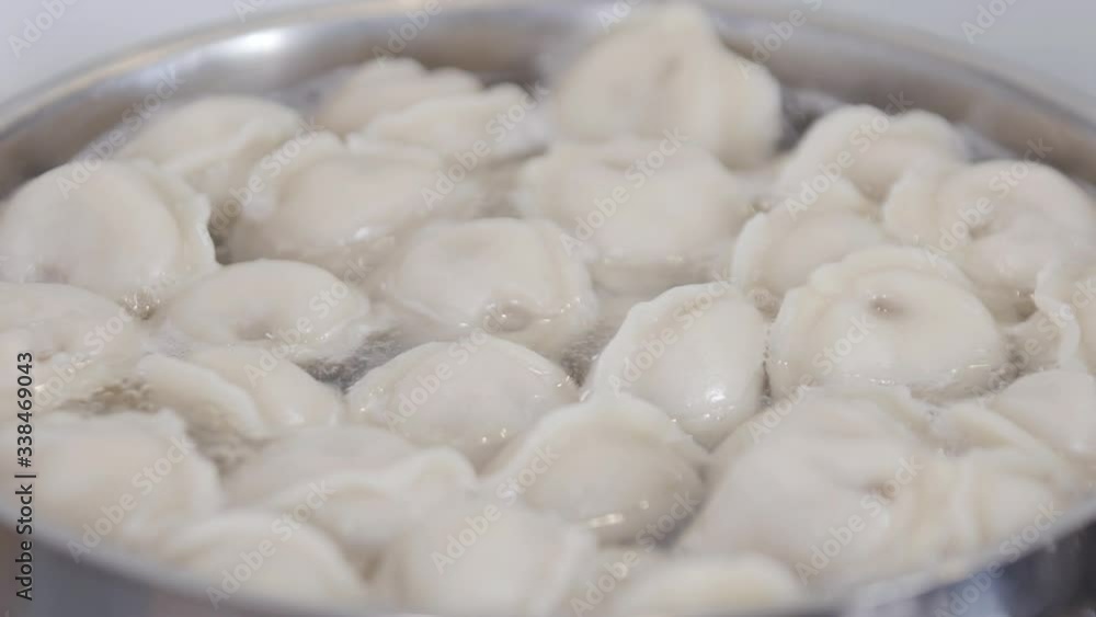 Process of cooking homemade dumplings. Meat dumplings in boiling water in a pan. Dumplings is traditional russian food. Food background. Close-up. Process of cooking homemade dumplings. Meat dumplings in boiling water in a pan. Dumplings is traditional russian food. Food background. Close-up.