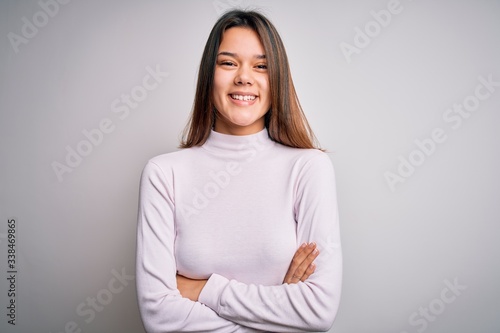Young beautiful brunette girl wearing casual sweater standing over isolated white background happy face smiling with crossed arms looking at the camera. Positive person.