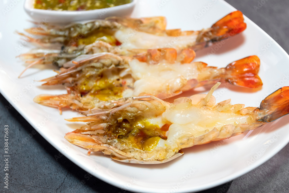 Charcoal grilled river prawns served with spicy seafood sauce on porcelain plate Charcoal grilled river prawns served with spicy seafood sauce on porcelain plate