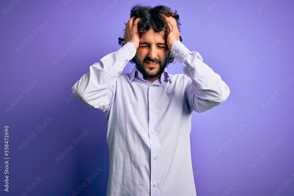 Young handsome business man with beard wearing shirt standing over purple background suffering from headache desperate and stressed because pain and migraine. Hands on head. Young handsome business man with beard wearing shirt standing over purple background suffering from headache desperate and stressed because pain and migraine. Hands on head.