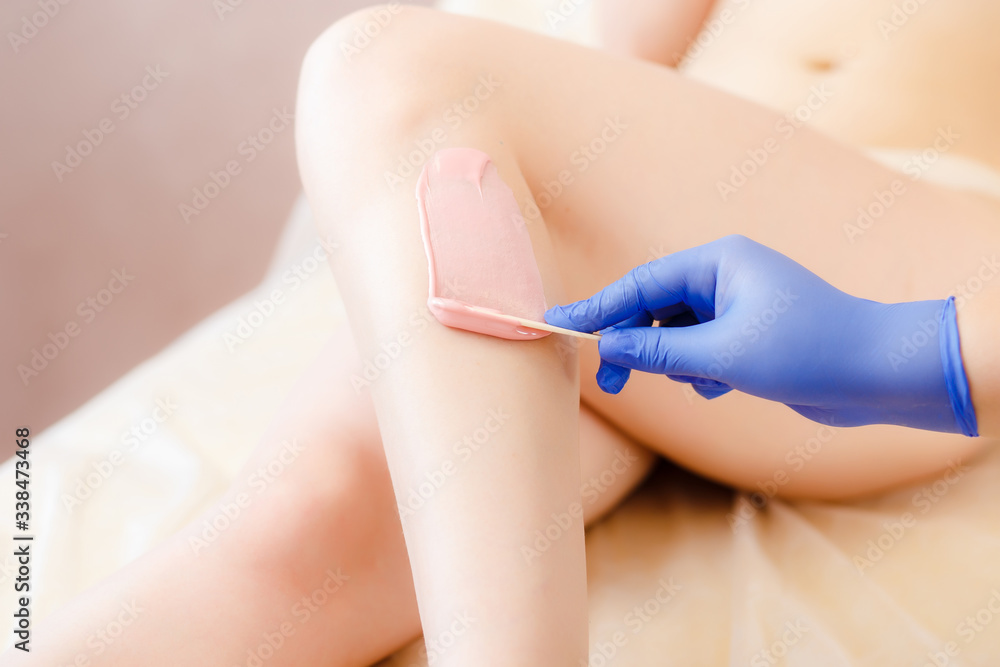 Fototapeta premium Close-up Of A Beautician Depilation With Hot Wax Woman's Leg In Beauty Spa. Body hair removal. Hair removal process on female leg with epilation.