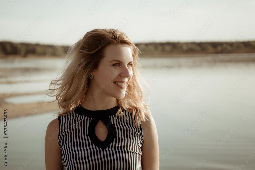 A young charming girl with hidden skin, happy eyes and a gentle smile looks into the distance while being outdoors during evening sunset. The happy face of a person in anticipation of good news. A young charming girl with hidden skin, happy eyes and a gentle smile looks into the distance while being outdoors during evening sunset. The happy face of a person in anticipation of good news.