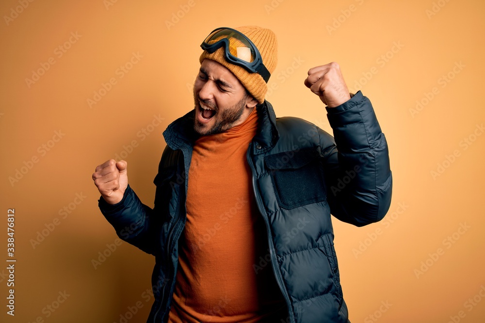 Young handsome skier man with beard wearing snow sportswear and ski goggles Dancing happy and cheerful, smiling moving casual and confident listening to music Young handsome skier man with beard wearing snow sportswear and ski goggles Dancing happy and cheerful, smiling moving casual and confident listening to music