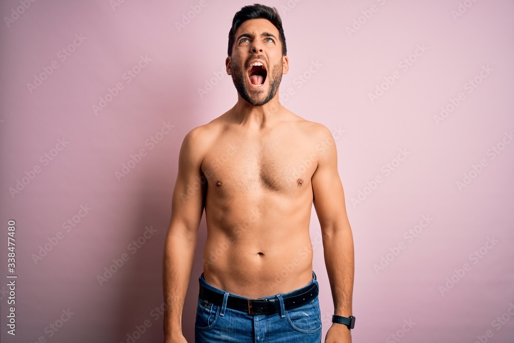 Young handsome strong man with beard shirtless standing over isolated pink background angry and mad screaming frustrated and furious, shouting with anger. Rage and aggressive concept. Young handsome strong man with beard shirtless standing over isolated pink background angry and mad screaming frustrated and furious, shouting with anger. Rage and aggressive concept.