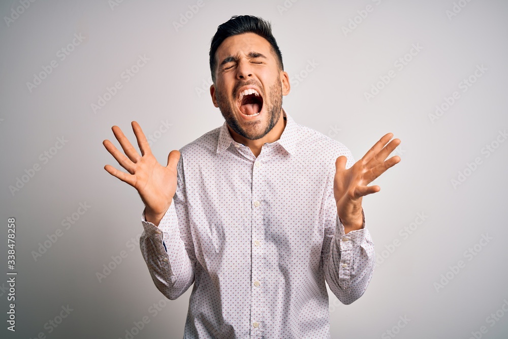 Young handsome man wearing elegant shirt standing over isolated white background celebrating mad and crazy for success with arms raised and closed eyes screaming excited. Winner concept