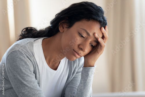 Sad and tired young african american girl hold her hand near head, feel sick or overworked, girl disappointed and crying alone, upset by bad news, problem and trouble, face close up