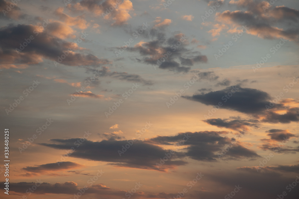 A cloudy sky on an sunny day at about sunset. The clouds are backlit in white an orange 
