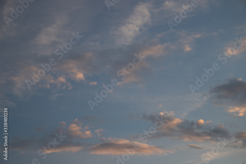A cloudy sky on an sunny day at about sunset. The clouds are backlit in white an orange 