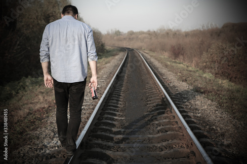 Man with alcohol on railway tracks outdoors. Depression disease. Economy crisis, poverty, unemployment concept. Consequences of coronavirus people isolation during quarantine. Hopelessness.