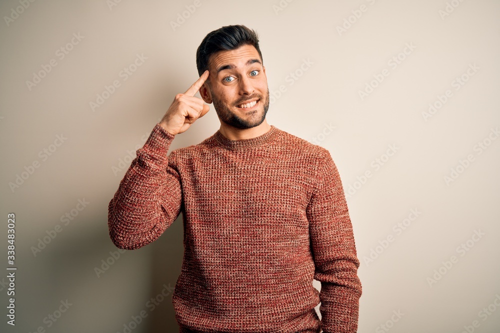 Fototapeta premium Young handsome man wearing casual sweater standing over isolated white background Smiling pointing to head with one finger, great idea or thought, good memory
