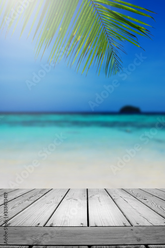 Fototapeta Naklejka Na Ścianę i Meble -  Blurred summer beach background with palm leaves and table wooden. 