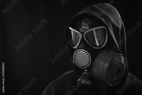 The girl is wearing a military gas mask. Isolated on a black background. Respiratory protection against harmful toxic substances, aerosols and viruses. Copy space, place for text. Black and white © Sergey
