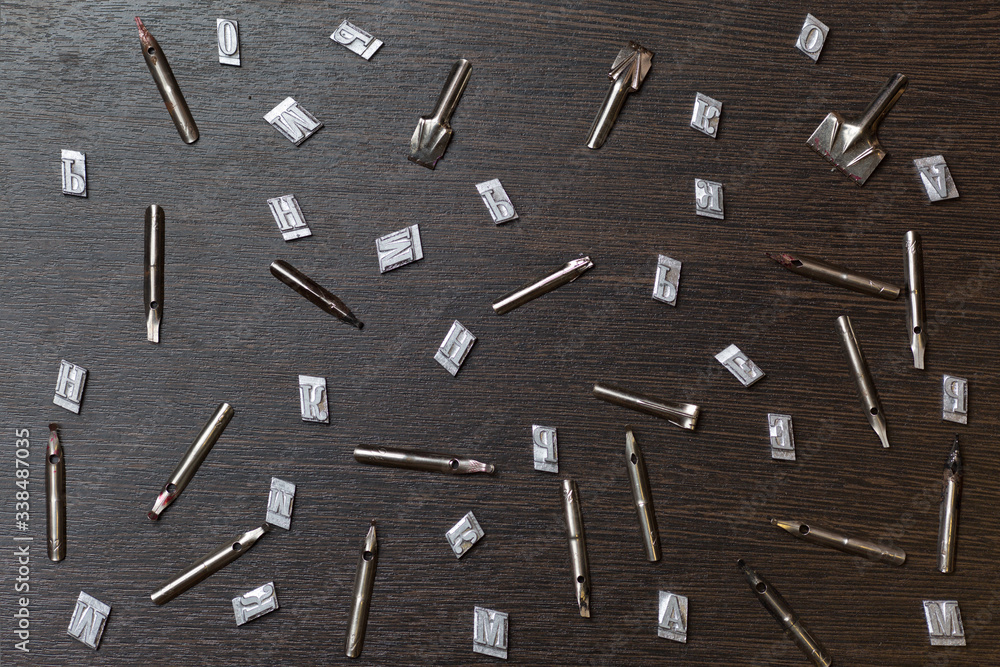 metal letters and spins for pens are scattered on a wooden table