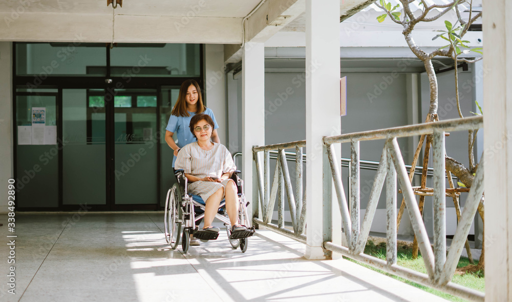 Smiling physiotherapist  taking care of the happy senior patient in wheelchair