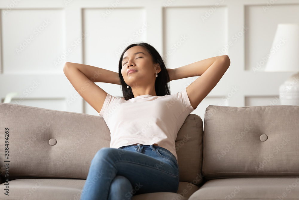Relaxed vietnamese woman put hands behind head resting leaned on sofa in cozy light warm living room, girl enjoy fresh conditioned air, reduce fatigue feels serene spend free lazy time at home concept Relaxed vietnamese woman put hands behind head resting leaned on sofa in cozy light warm living room, girl enjoy fresh conditioned air, reduce fatigue feels serene spend free lazy time at home concept
